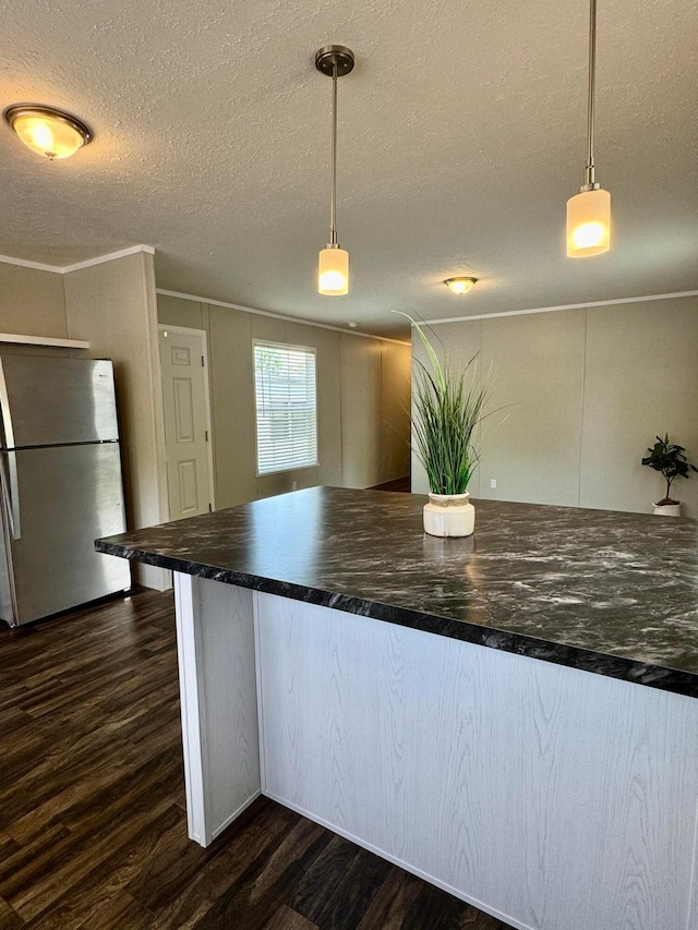 kitchen with freestanding refrigerator, dark wood-style floors, dark countertops, a textured ceiling, and pendant lighting