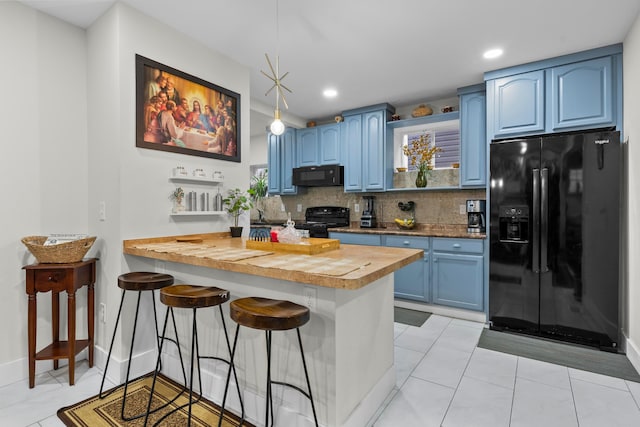 kitchen featuring black appliances, blue cabinetry, butcher block countertops, and recessed lighting