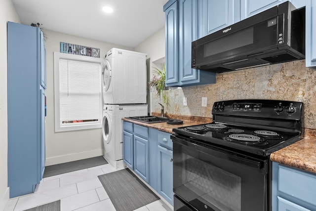 kitchen with black appliances, stacked washer and clothes dryer, blue cabinets, backsplash, and baseboards