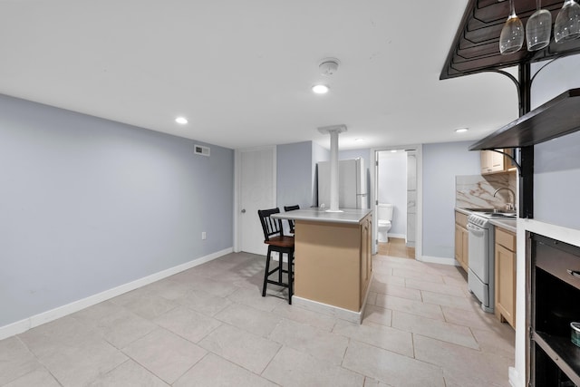 kitchen featuring white electric range oven, light countertops, a breakfast bar area, recessed lighting, and baseboards