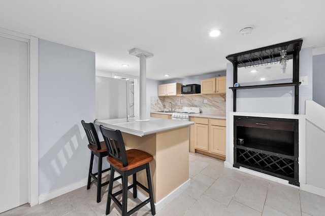 kitchen with black microwave, light brown cabinets, tasteful backsplash, light countertops, and a sink