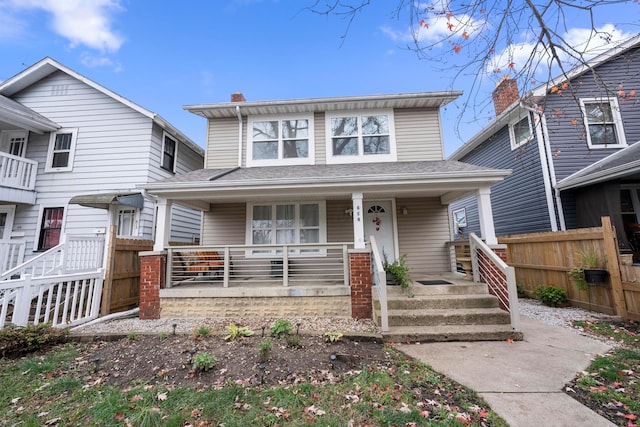 american foursquare style home featuring a porch, fence, and a chimney