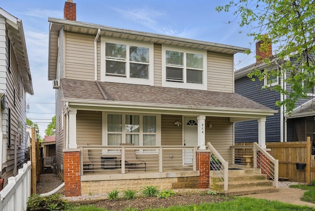 view of front of home with covered porch, fence, and a chimney