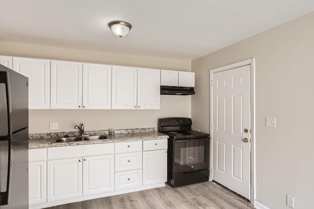 kitchen featuring electric range, under cabinet range hood, freestanding refrigerator, a sink, and white cabinets