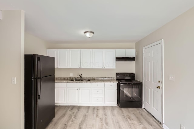kitchen featuring black appliances, under cabinet range hood, a sink, white cabinets, and light wood-type flooring