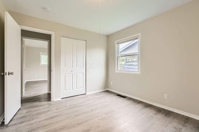 unfurnished bedroom with baseboards, light wood-style flooring, and a closet