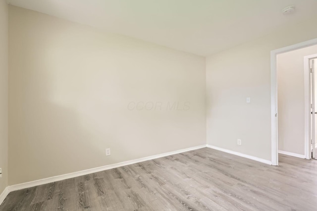 spare room with wood finished floors, baseboards, and a smoke detector