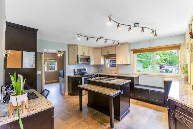 200 Park Ave, New Lexington, OH 43764 - kitchen with stainless steel appliances, a sink, cream cabinets, light stone counters, and a kitchen island with sink