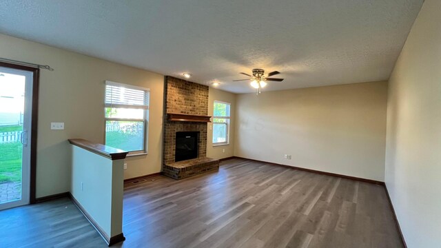 7586 Jenkins Dr, Canal Winchester, OH 43110 - unfurnished living room featuring wood finished floors, a ceiling fan, baseboards, a textured ceiling, and a fireplace
