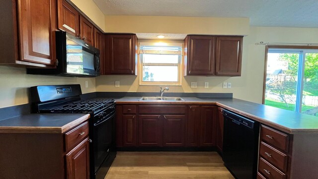 7586 Jenkins Dr, Canal Winchester, OH 43110 - kitchen with black appliances, a sink, a peninsula, light wood-style floors, and dark countertops