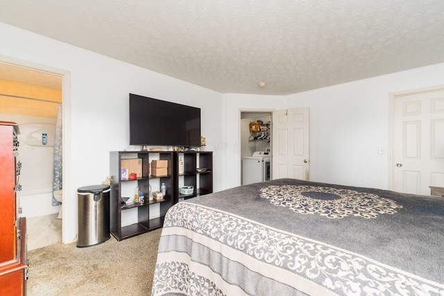 carpeted bedroom featuring washer / clothes dryer, a textured ceiling, and ensuite bath