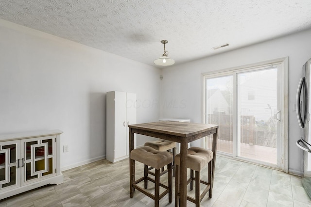 dining area featuring a textured ceiling and baseboards