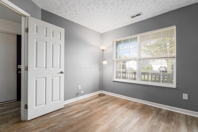 empty room featuring wood finished floors, a textured ceiling, and baseboards