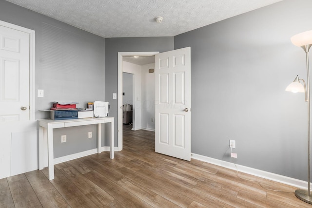 bedroom with wood finished floors, baseboards, and a textured ceiling