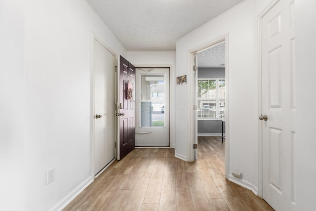 entryway featuring light wood-style floors, baseboards, and a textured ceiling