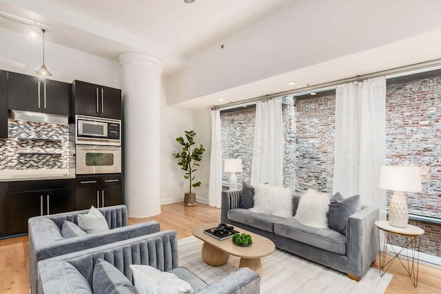 106 N High St Unit 504, Columbus, OH 43215 - living area with ornate columns, light wood-style floors, baseboards, and brick wall