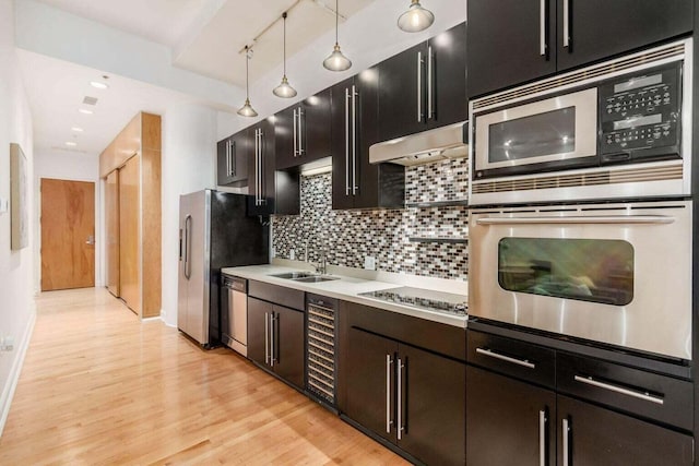 106 N High St Unit 504, Columbus, OH 43215 - kitchen with appliances with stainless steel finishes, a sink, under cabinet range hood, light wood-type flooring, and decorative backsplash