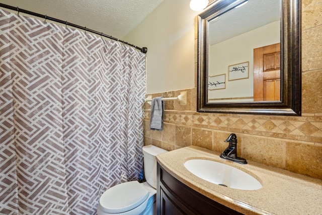 7684 Stout Rd, Circleville, OH 43113 - bathroom with toilet, a textured ceiling, vanity, tile walls, and wainscoting