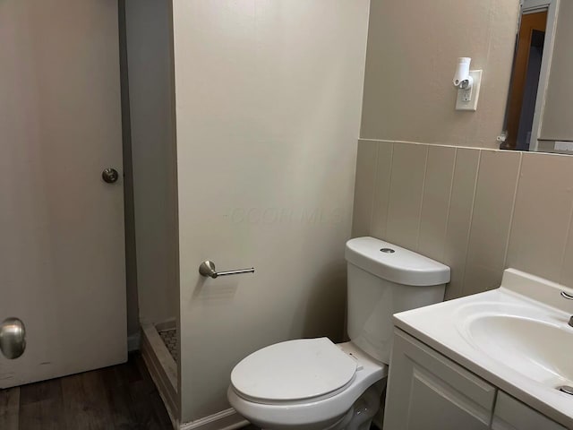 full bath with toilet, vanity, a shower stall, and wood finished floors