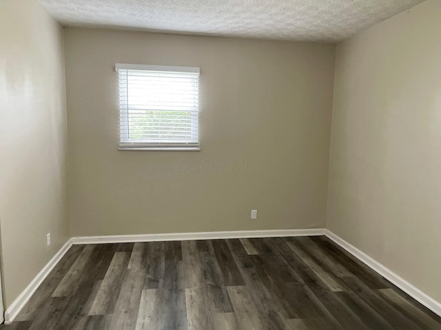 spare room featuring dark wood finished floors and baseboards