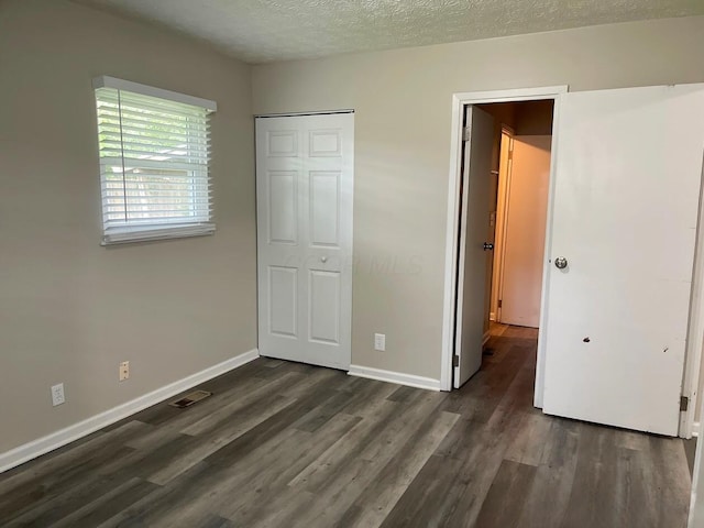 unfurnished bedroom featuring dark wood finished floors, baseboards, and a textured ceiling