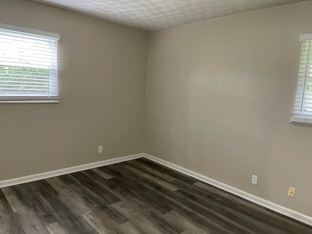 spare room with dark wood-type flooring, baseboards, and a textured ceiling