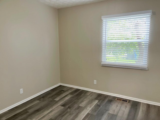 spare room with dark wood-type flooring and baseboards