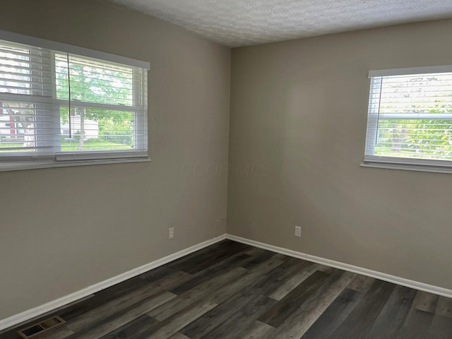 spare room with dark wood-style floors, baseboards, and a textured ceiling