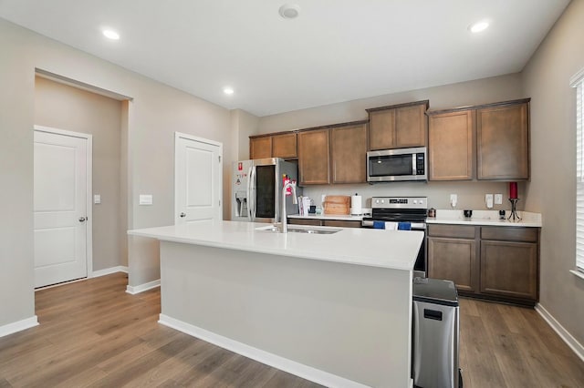 4410 Holstein Dr, Columbus, OH 43207 - kitchen featuring stainless steel appliances, a sink, baseboards, wood finished floors, and an island with sink