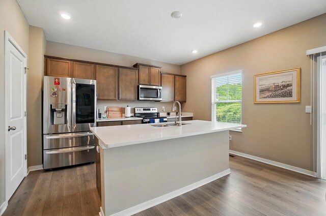 4410 Holstein Dr, Columbus, OH 43207 - kitchen with stainless steel appliances, wood finished floors, light countertops, a sink, and a center island with sink