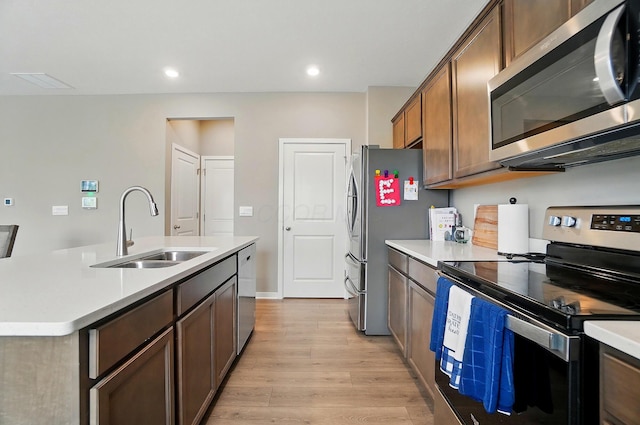 4410 Holstein Dr, Columbus, OH 43207 - kitchen featuring stainless steel appliances, a sink, light wood finished floors, light countertops, and a center island with sink