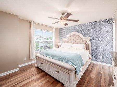 592 Summer Tree Loop, Marysville, OH 43040 - bedroom with an accent wall, wallpapered walls, baseboards, wood finished floors, and a ceiling fan