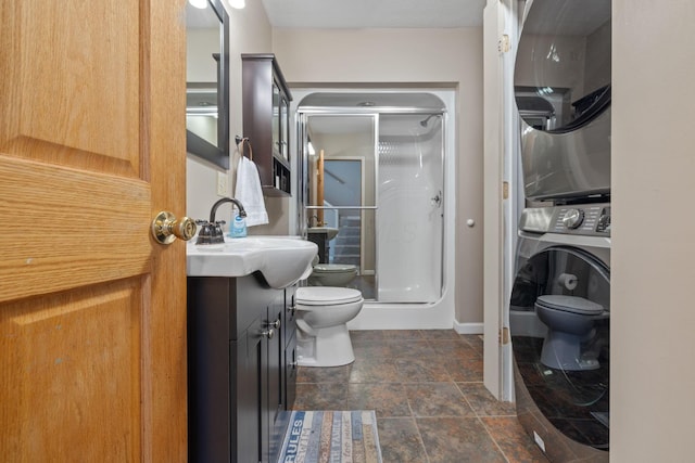 bathroom with stacked washer and clothes dryer, toilet, a stall shower, and vanity