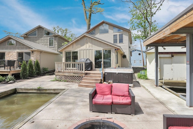 back of house with a hot tub, a deck, a patio, and board and batten siding