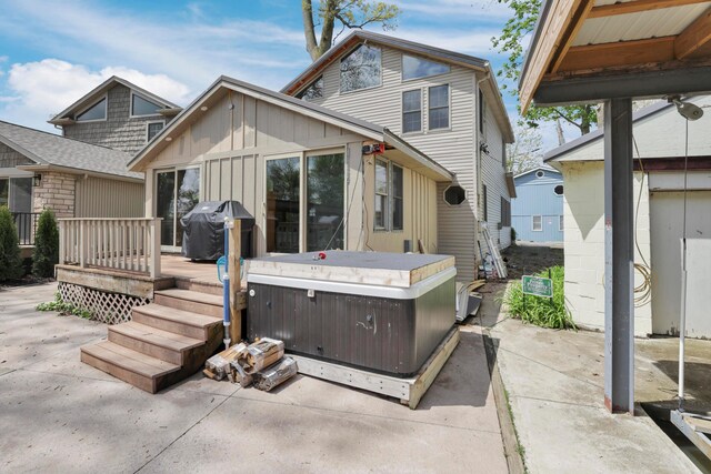 rear view of property with a hot tub, a patio, and a wooden deck