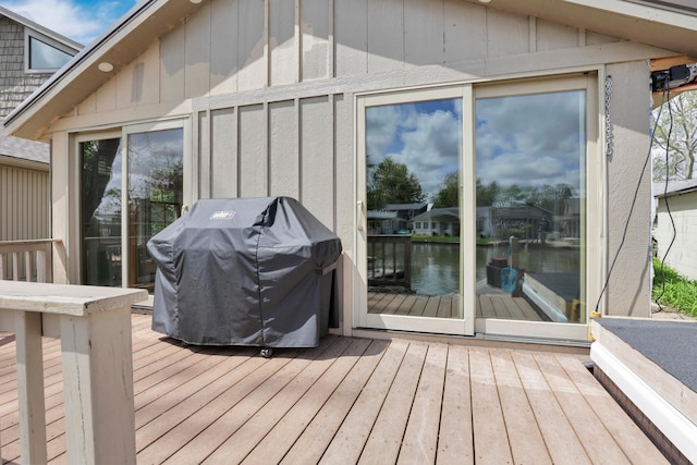 deck with area for grilling and a water view