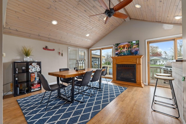 dining area with a glass covered fireplace, wood ceiling, plenty of natural light, recessed lighting, and lofted ceiling