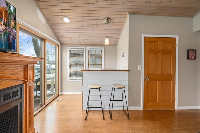 dining area with wood ceiling, vaulted ceiling, baseboards, and light wood-style floors