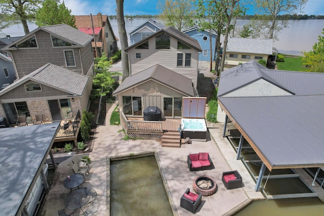 rear view of house featuring a deck with water view, an outdoor fire pit, a residential view, and a patio