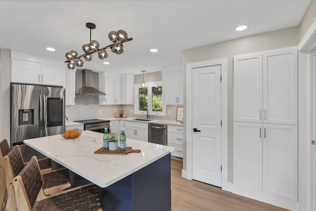 2095 Mccoy Rd, Upper Arlington, OH 43220 - kitchen with wall chimney range hood, appliances with stainless steel finishes, a sink, white cabinets, and a center island