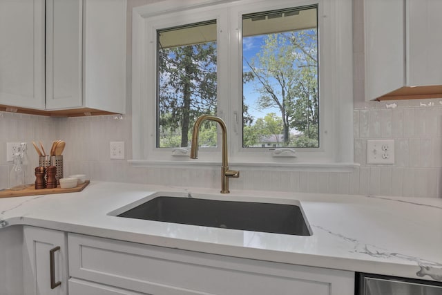 2095 Mccoy Rd, Upper Arlington, OH 43220 - kitchen view of a sink, decorative backsplash, light stone counters, and white cabinetry