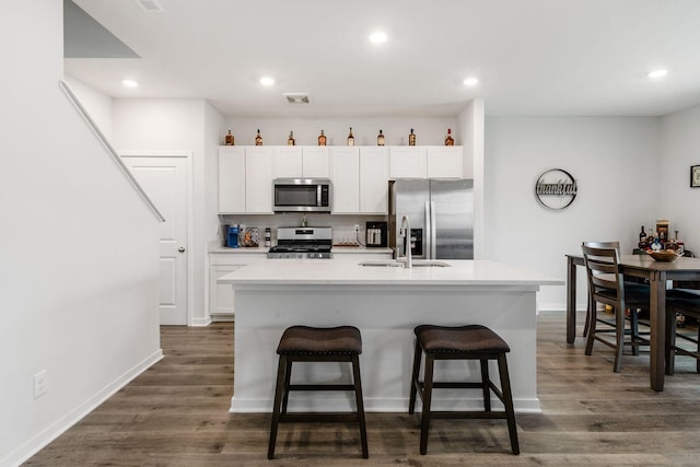 6355 Marinelli Dr N, Columbus, OH 43228 - kitchen featuring appliances with stainless steel finishes, a kitchen island with sink, a kitchen bar, white cabinetry, and recessed lighting