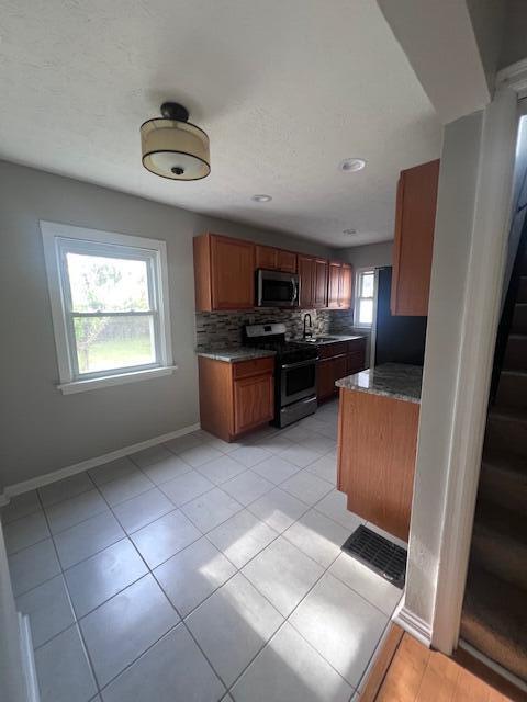 985 S Yearling Rd, Columbus, OH 43227 - kitchen with stainless steel appliances, backsplash, a sink, baseboards, and brown cabinets