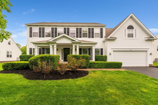 5073 Thornwood Dr, Westerville, OH 43082 - colonial home with a garage, asphalt driveway, a front lawn, and roof with shingles