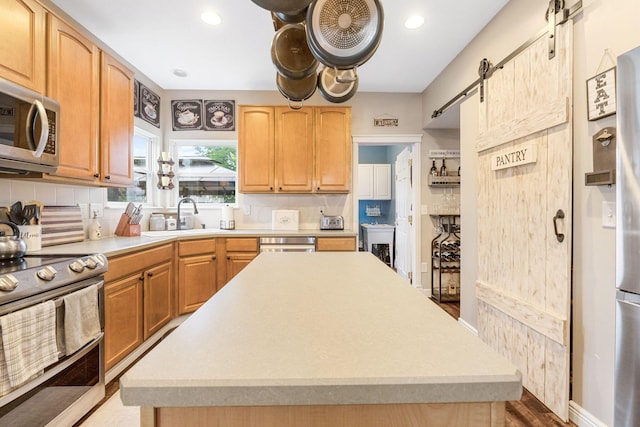 5073 Thornwood Dr, Westerville, OH 43082 - kitchen featuring stainless steel appliances, a sink, light countertops, a barn door, and tasteful backsplash