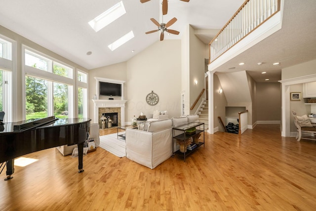 504 W Orange Rd, Delaware, OH 43015 - living area featuring high vaulted ceiling, light wood-style flooring, a tile fireplace, a ceiling fan, and stairs