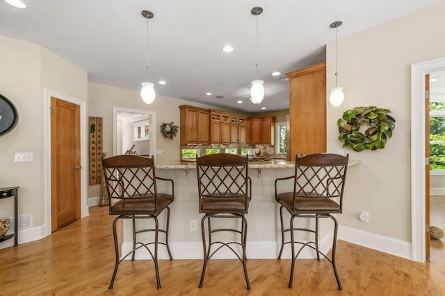 504 W Orange Rd, Delaware, OH 43015 - kitchen featuring light wood finished floors, a peninsula, a kitchen breakfast bar, healthy amount of natural light, and recessed lighting