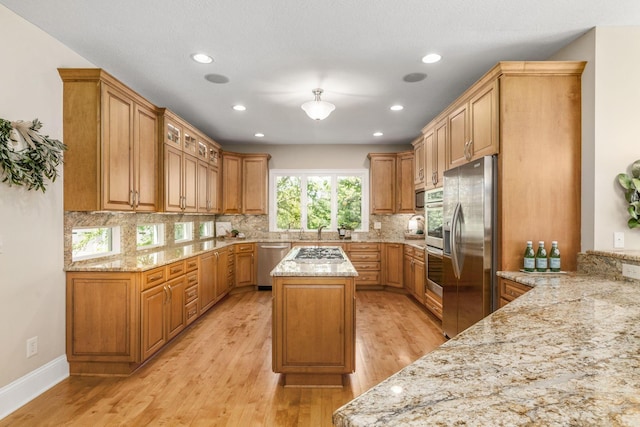 504 W Orange Rd, Delaware, OH 43015 - kitchen with stainless steel appliances, light wood-style floors, light stone counters, tasteful backsplash, and a center island
