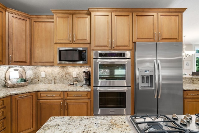 504 W Orange Rd, Delaware, OH 43015 - kitchen featuring appliances with stainless steel finishes, light stone counters, decorative backsplash, and brown cabinetry