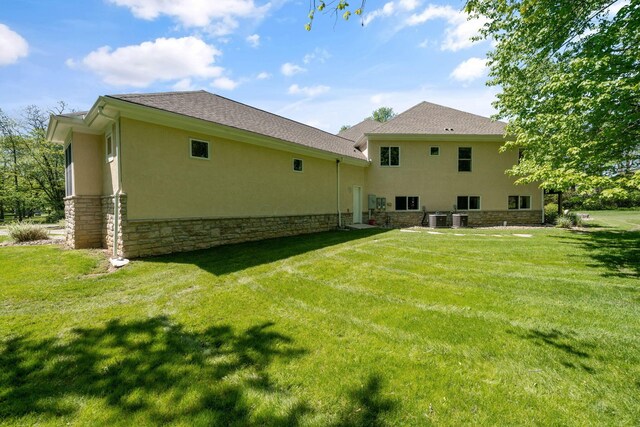 504 W Orange Rd, Delaware, OH 43015 - rear view of house featuring stucco siding, a lawn, stone siding, and central AC unit